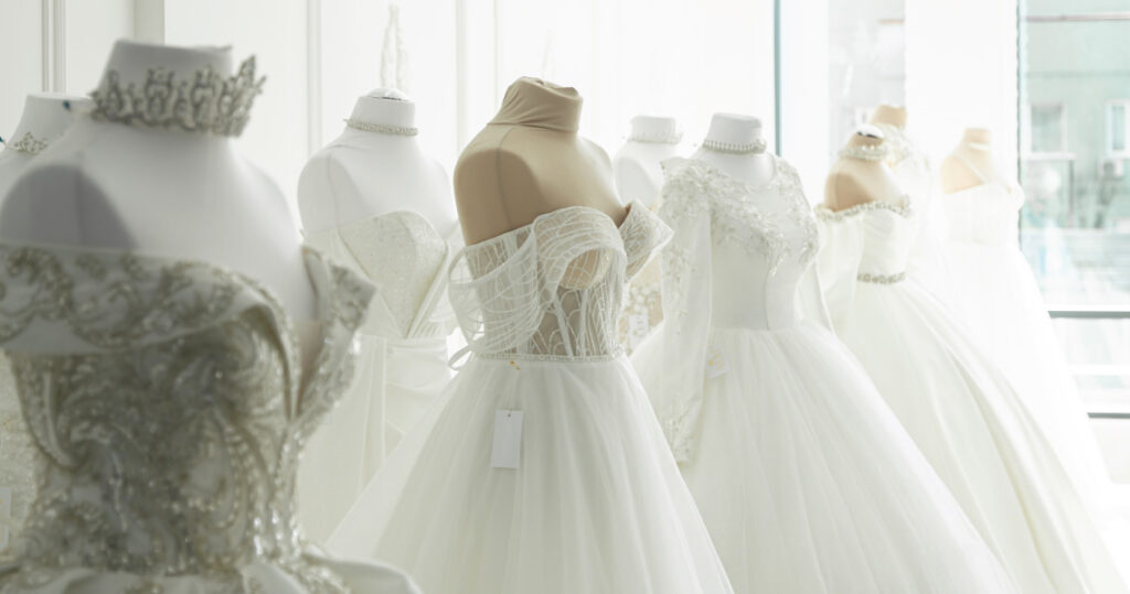 Photographic image of wedding dresses on mannequins in a shop.