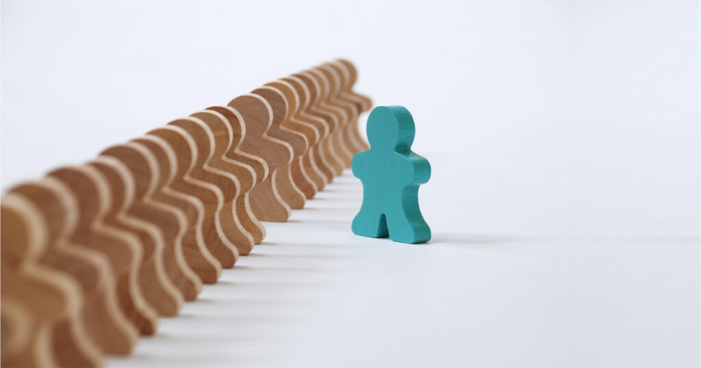 A row of wooden figures, with one green figure pulled out on its own to the right of the others