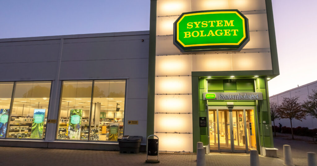 Photograph of a System Bolaget shop selling alcohol in Sweden, lit up in the early evening. Credit: ChristianLphoto / Shutterstock.com