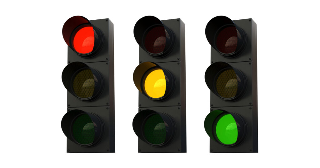 A set of 3 traffic lights on a white background. The first is showing a red light, the second an amber light and the third a green light